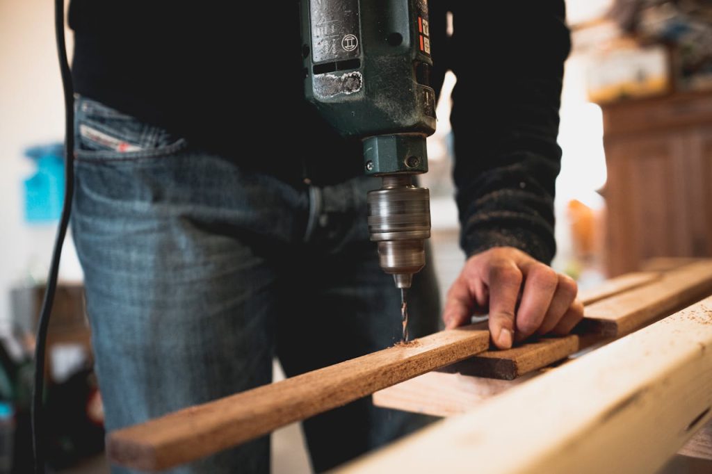 Crafting Captivating Headlines: Your awesome post title goes here Close-up of a person using an electric drill on a wooden plank, showcasing detailed woodworking skills.